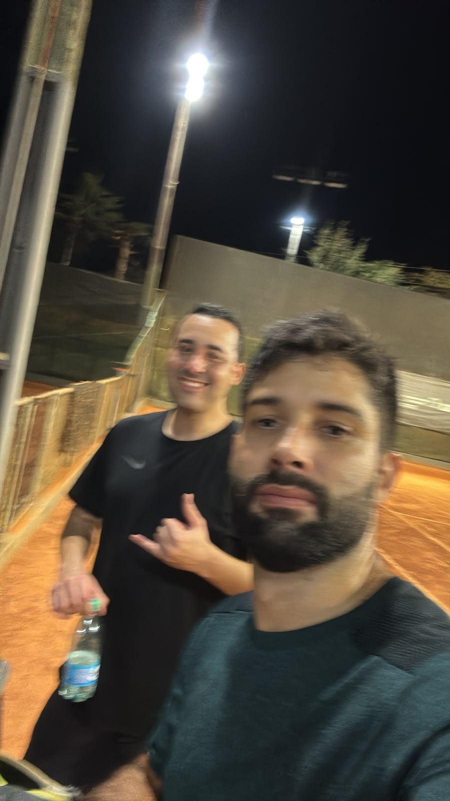 Dupla posando após o jogo na quadra de saibro à noite